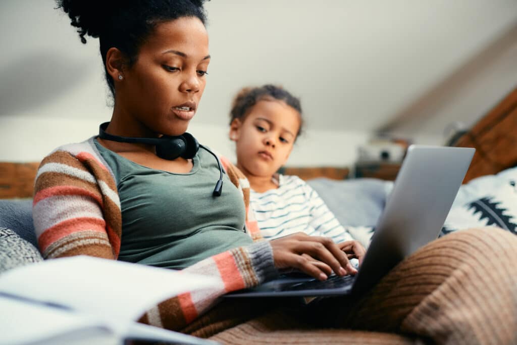 African American mother using laptop while working from home.