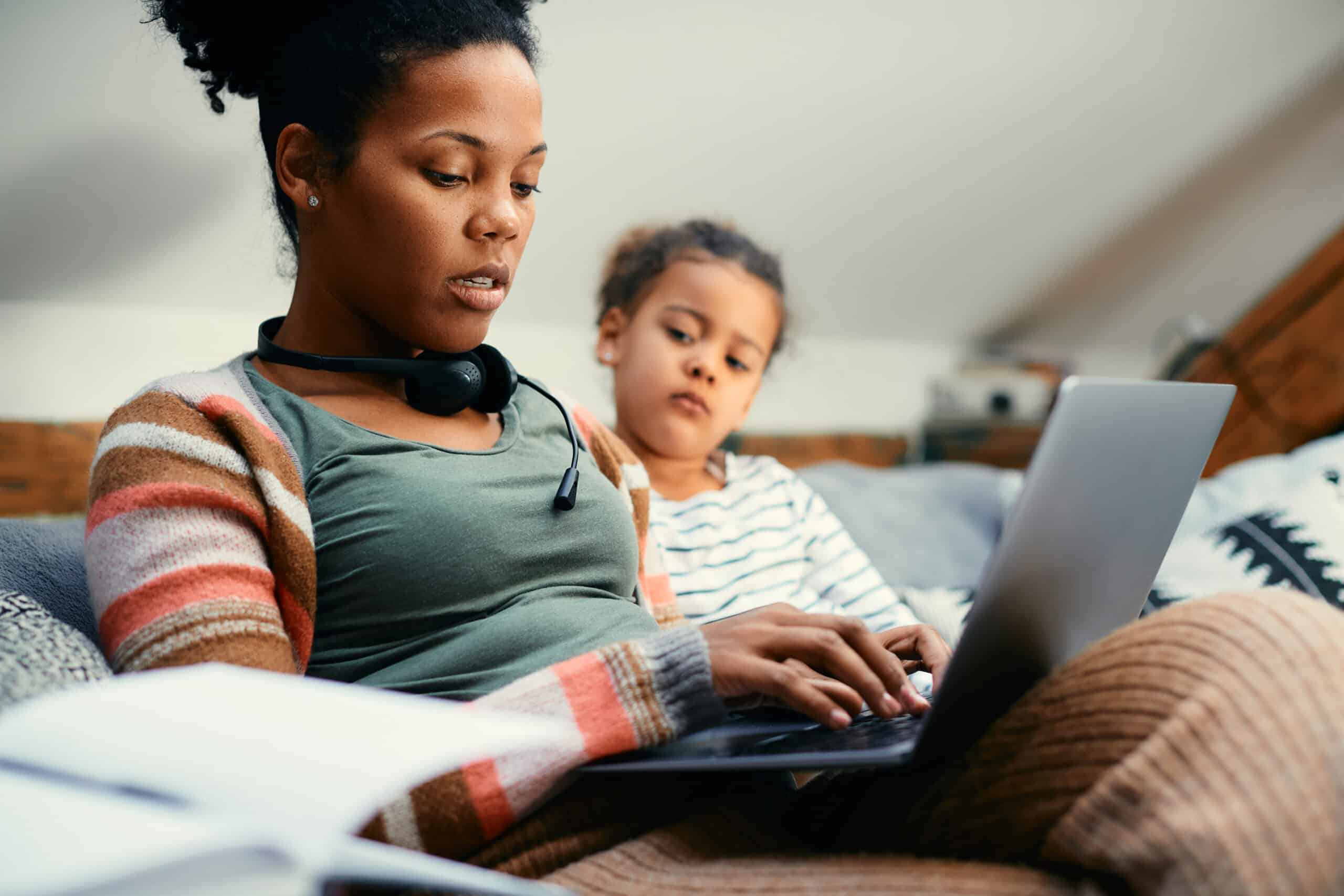 African American mother using laptop while working from home.